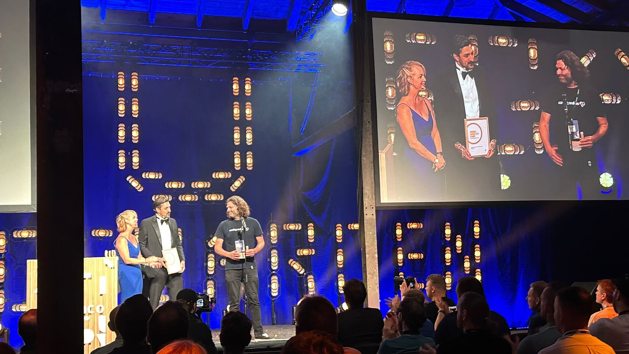 Ollie on stage receiving an Umbraco Award for Best Commerce Solution on behalf of Enjoy Digital's Camira Fabrics